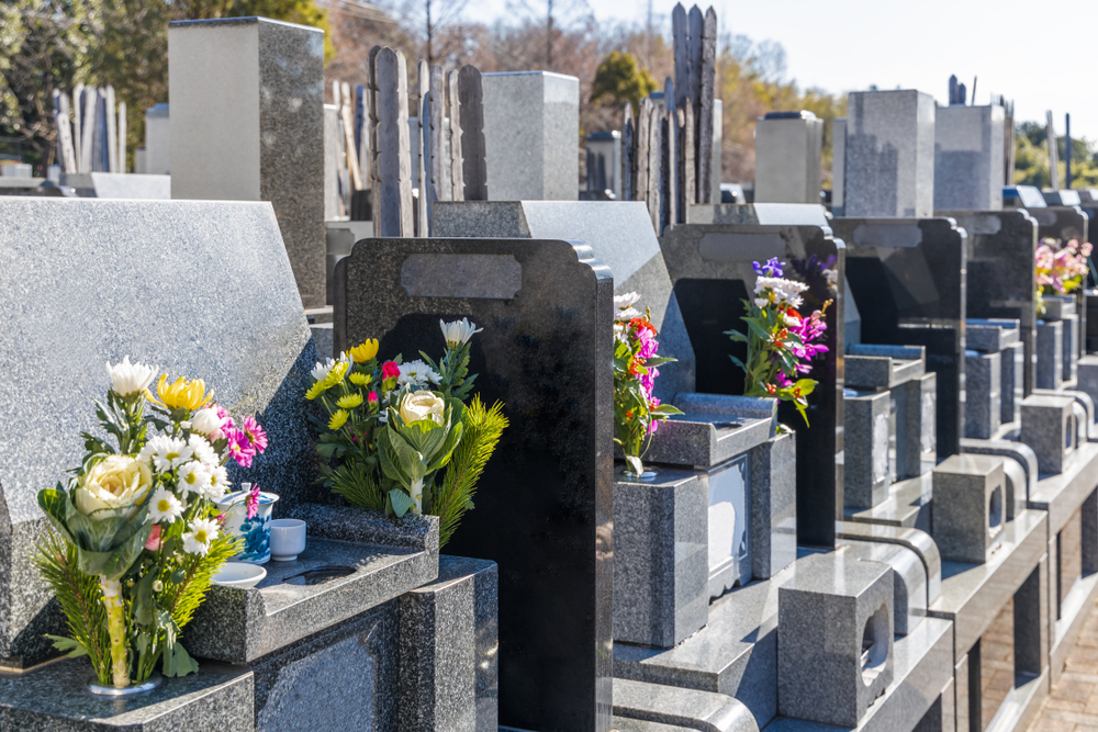 A row of memorials and tombstones closely lined up together in a graveyard